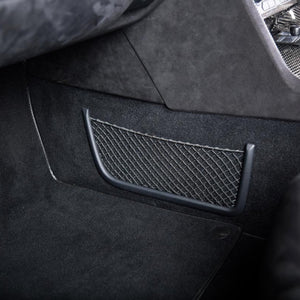 Plastic frame elastic net in the footwell of a car.
