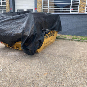 Skip net with bungee cord covering a stationary skip.