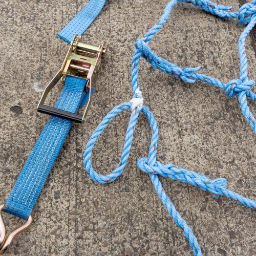 Blue knotted net with webbing and ratchet strap with hooo