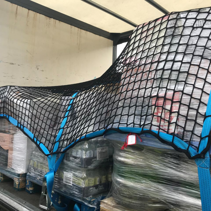 Heavy duty cargo net with webbing and integrated fittings in use as a pallet load control net.