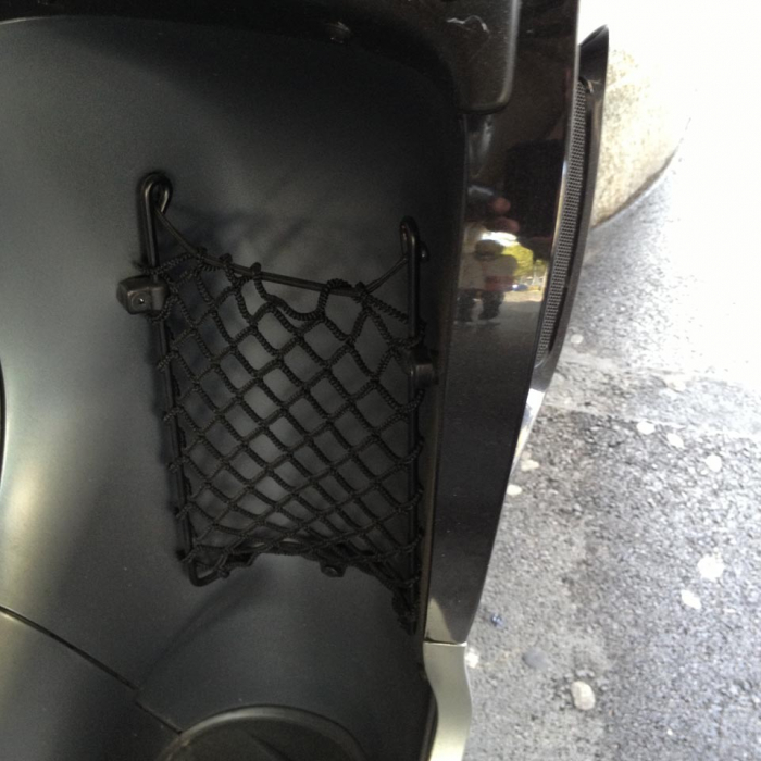 Close-up of small bespoke elastic net to provide storage for a water bottle on a motorcycle